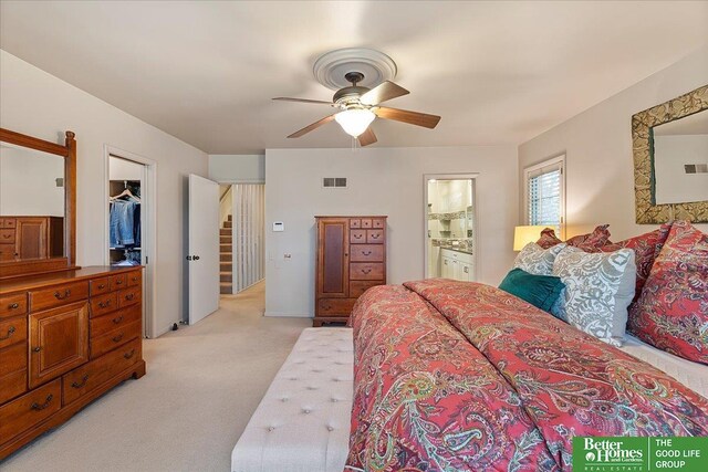 bedroom with ceiling fan, connected bathroom, visible vents, a spacious closet, and light carpet