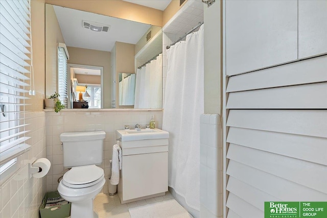 full bathroom featuring tile patterned flooring, vanity, toilet, tile walls, and visible vents