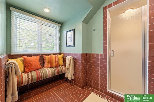 bathroom featuring tile walls, a shower stall, and a wainscoted wall