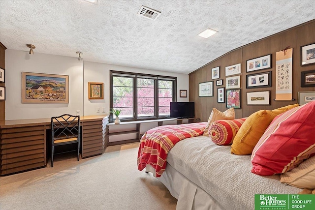 bedroom featuring light carpet, visible vents, a textured ceiling, wood walls, and vaulted ceiling