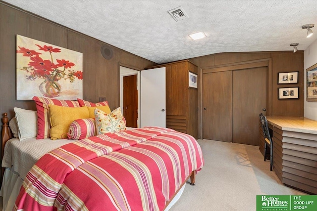 bedroom featuring wooden walls, visible vents, light carpet, and a closet