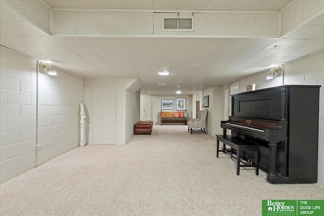 sitting room with visible vents, carpet flooring, and concrete block wall