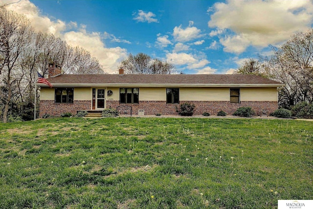 ranch-style house with brick siding, a front lawn, and a chimney