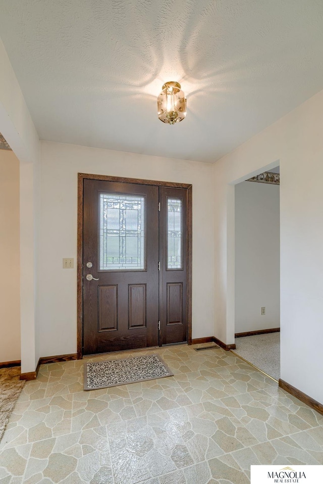 foyer entrance featuring stone finish floor and baseboards