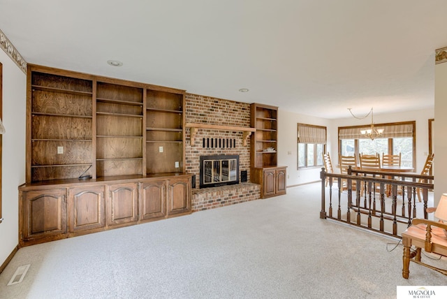 unfurnished living room featuring visible vents, a fireplace, carpet floors, baseboards, and an inviting chandelier