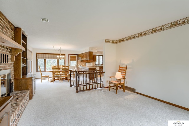 living area featuring carpet flooring, baseboards, and a notable chandelier