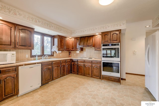 kitchen featuring stone finish floor, backsplash, a sink, premium range hood, and white appliances