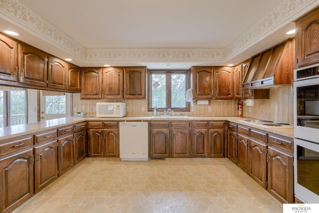 kitchen featuring a sink, stone finish floor, white appliances, and light countertops