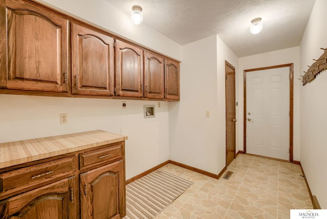 laundry room with electric dryer hookup, a textured ceiling, cabinet space, baseboards, and hookup for a washing machine