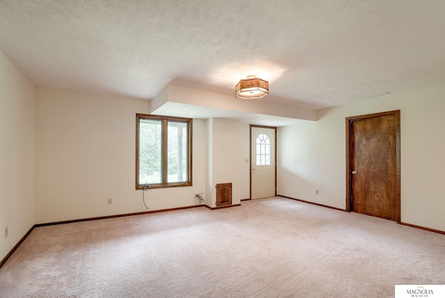 unfurnished room with baseboards, a textured ceiling, and light colored carpet