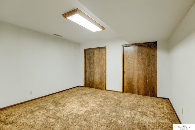 unfurnished bedroom featuring visible vents, carpet, multiple closets, and baseboards
