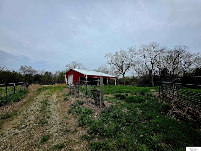 view of yard with fence, a pole building, an outdoor structure, and a rural view