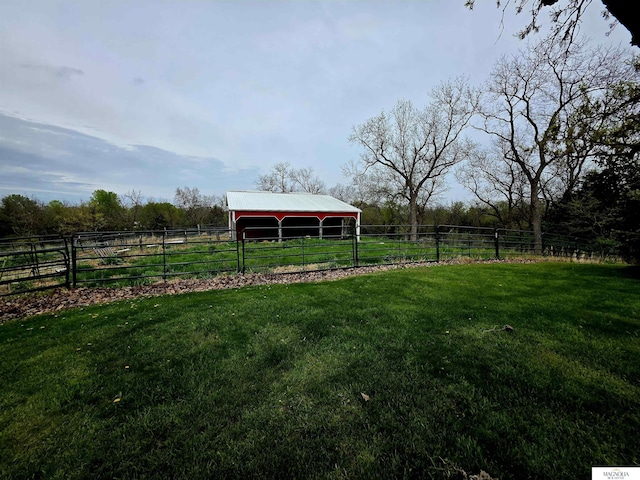 view of yard with fence, a rural view, a pole building, and an outdoor structure