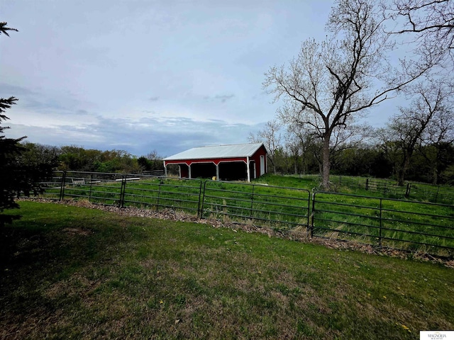view of yard featuring fence, a pole building, an outbuilding, and a rural view