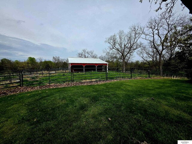 view of yard with fence, a rural view, a pole building, and an outdoor structure