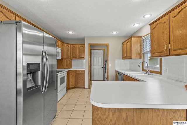 kitchen with a peninsula, light countertops, a sink, appliances with stainless steel finishes, and backsplash