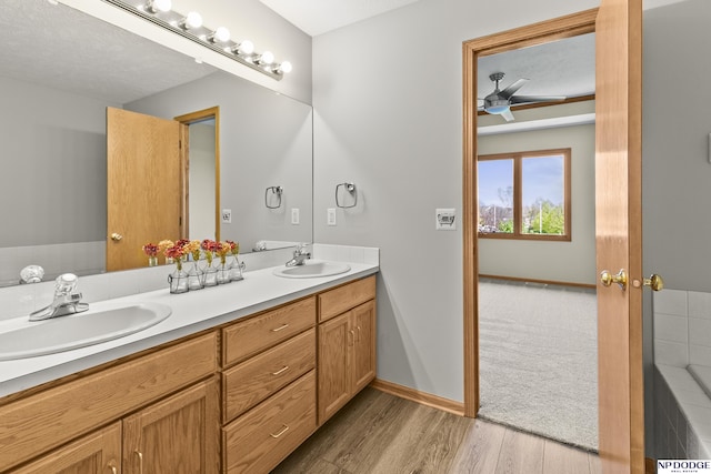 bathroom with a sink, ceiling fan, double vanity, and wood finished floors