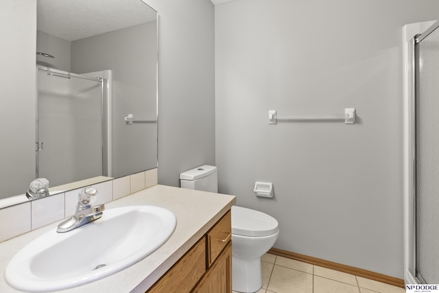 bathroom featuring tile patterned flooring, a shower stall, vanity, baseboards, and toilet