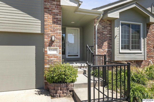 view of exterior entry with brick siding and a garage