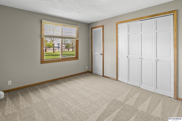 unfurnished bedroom featuring baseboards, carpet flooring, multiple closets, and a textured ceiling