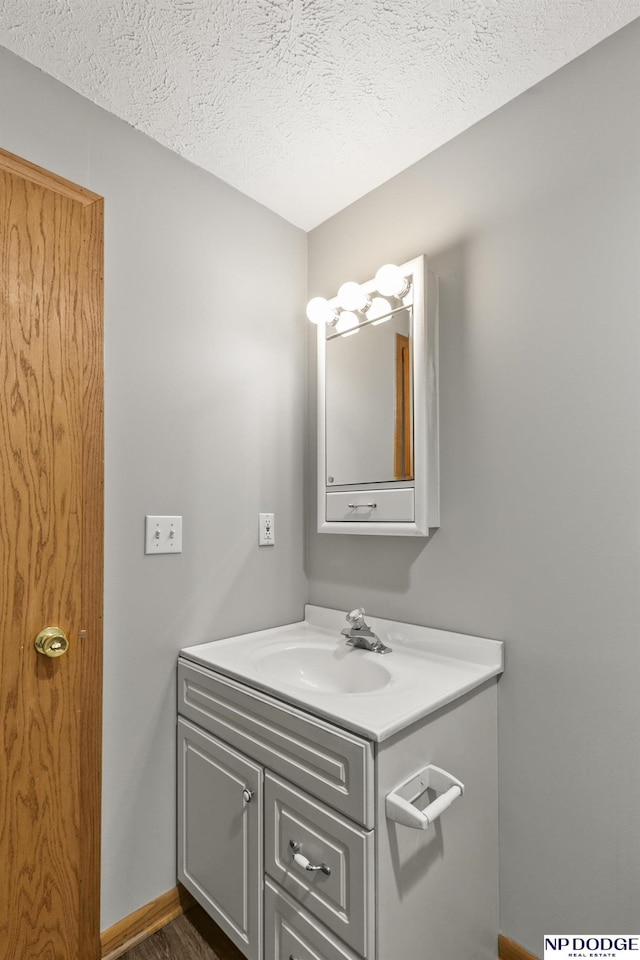 bathroom with vanity, baseboards, and a textured ceiling