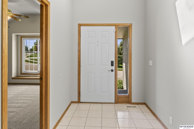 entryway with baseboards, ceiling fan, light tile patterned flooring, and visible vents