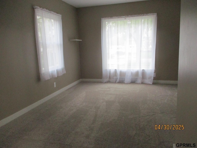 carpeted empty room with baseboards and a wealth of natural light