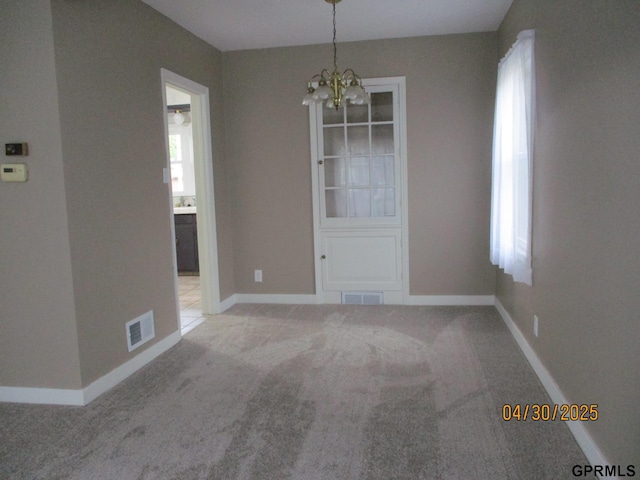 unfurnished dining area featuring an inviting chandelier, carpet floors, baseboards, and visible vents