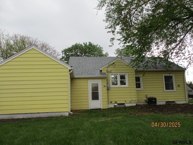 back of property featuring a lawn, cooling unit, and a shingled roof