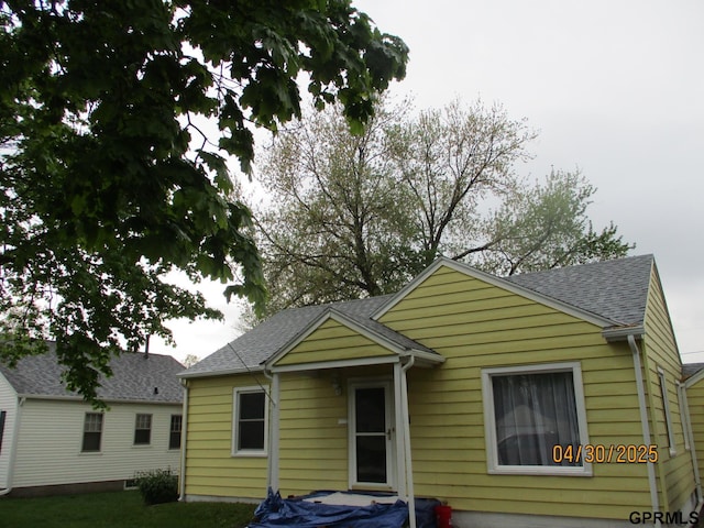 bungalow featuring roof with shingles