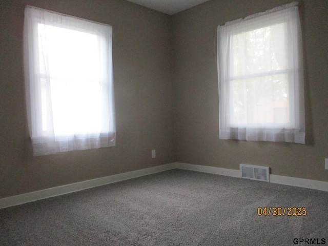 empty room featuring baseboards, visible vents, and carpet