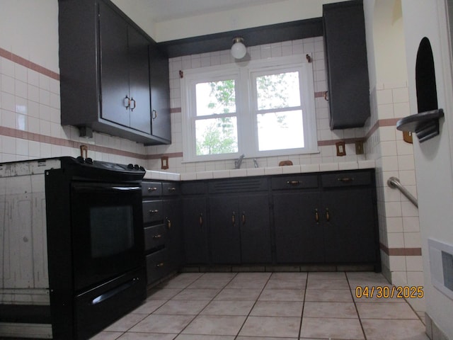 kitchen with dark cabinetry, tile counters, black electric range oven, and light tile patterned floors