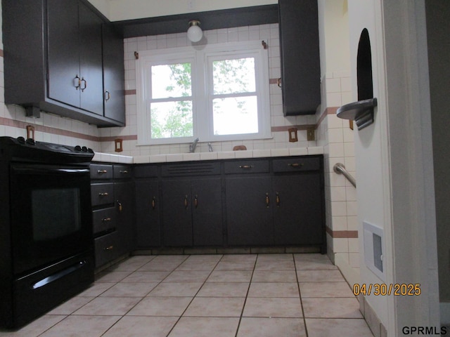 kitchen with light tile patterned flooring, dark cabinets, tile countertops, decorative backsplash, and black range with electric stovetop
