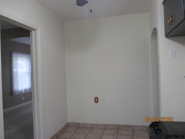 unfurnished room featuring arched walkways, ceiling fan, and light tile patterned flooring