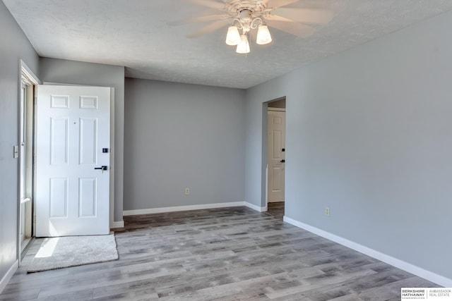 spare room with a textured ceiling, baseboards, ceiling fan, and wood finished floors