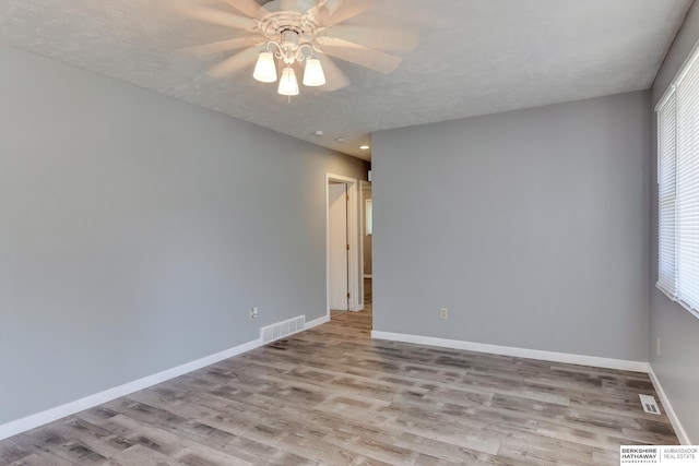 unfurnished room featuring visible vents, a ceiling fan, baseboards, and wood finished floors