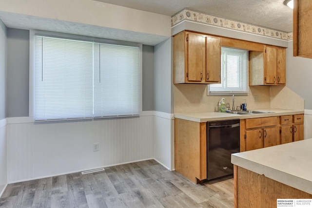 kitchen with visible vents, dishwasher, light countertops, a wainscoted wall, and light wood finished floors