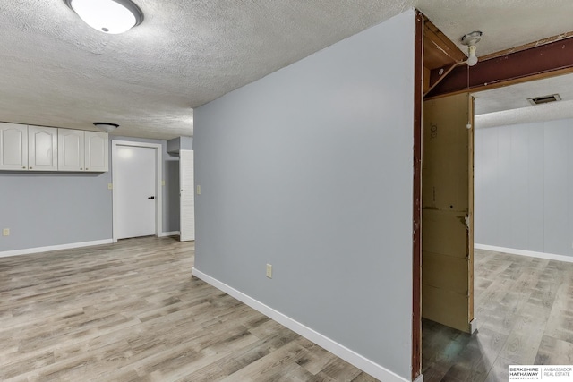 interior space featuring a textured ceiling, visible vents, and light wood-style flooring