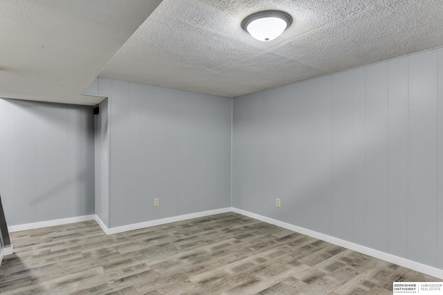 basement with baseboards, visible vents, a textured ceiling, and wood finished floors
