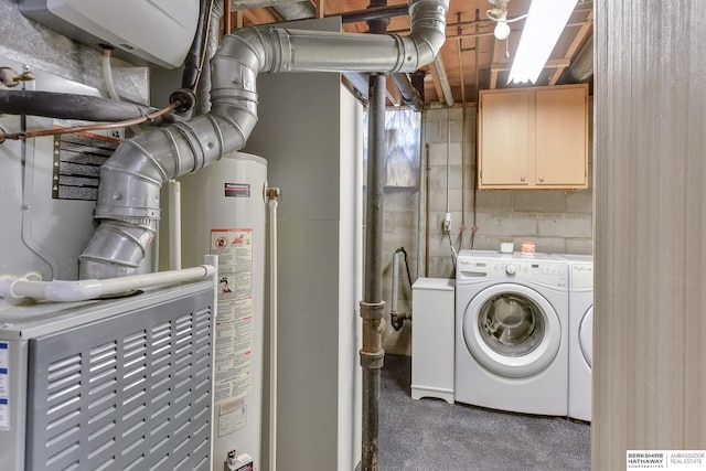 laundry room featuring cabinet space, gas water heater, concrete block wall, and washing machine and clothes dryer