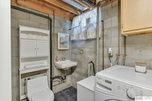 bathroom with a sink, washer / clothes dryer, toilet, and concrete block wall