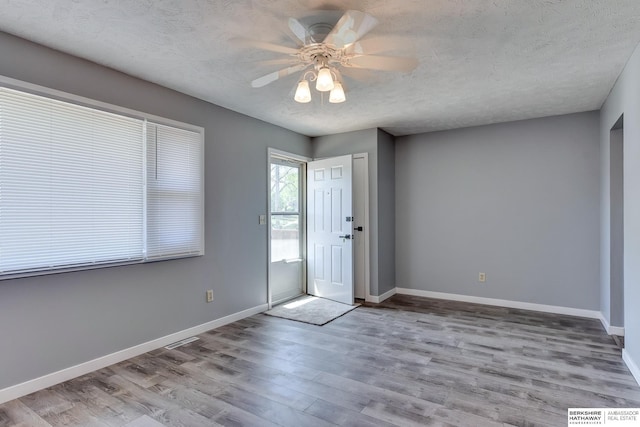 entrance foyer featuring visible vents, baseboards, a textured ceiling, and wood finished floors