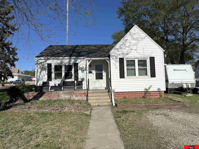 bungalow with a porch and roof with shingles