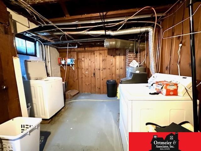 unfinished below grade area featuring wooden walls and independent washer and dryer