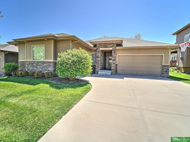prairie-style house featuring a garage, a front yard, stone siding, and concrete driveway