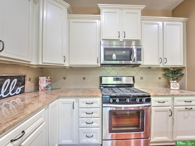 kitchen featuring decorative backsplash, white cabinetry, light stone countertops, and stainless steel appliances