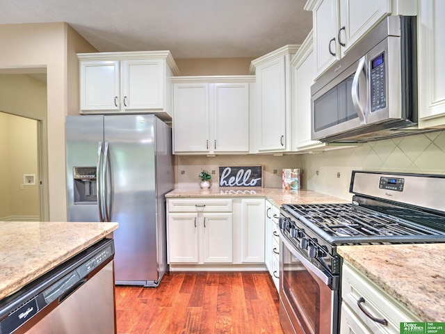 kitchen featuring backsplash, appliances with stainless steel finishes, wood finished floors, and white cabinets
