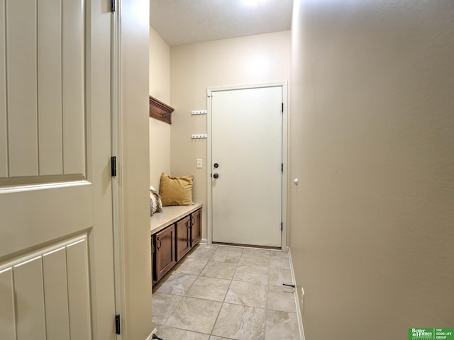mudroom featuring baseboards, a textured ceiling, and marble finish floor