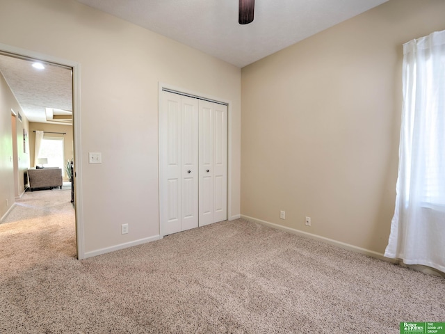 unfurnished bedroom featuring baseboards, carpet flooring, and a closet
