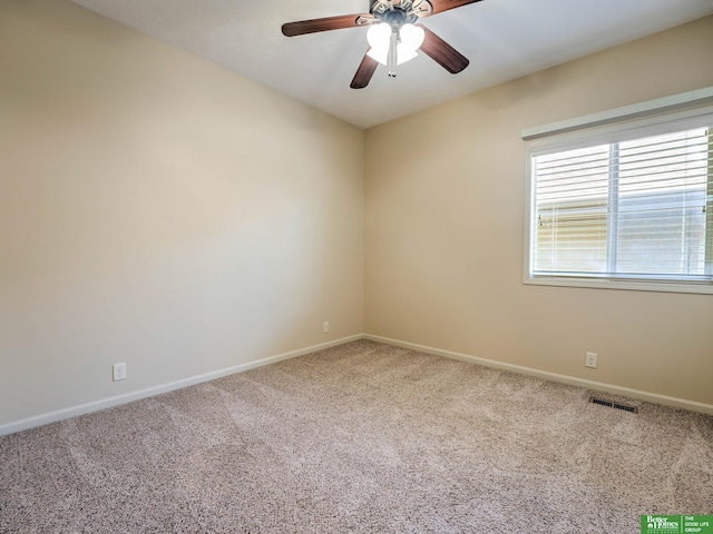 carpeted spare room with baseboards, a ceiling fan, and visible vents